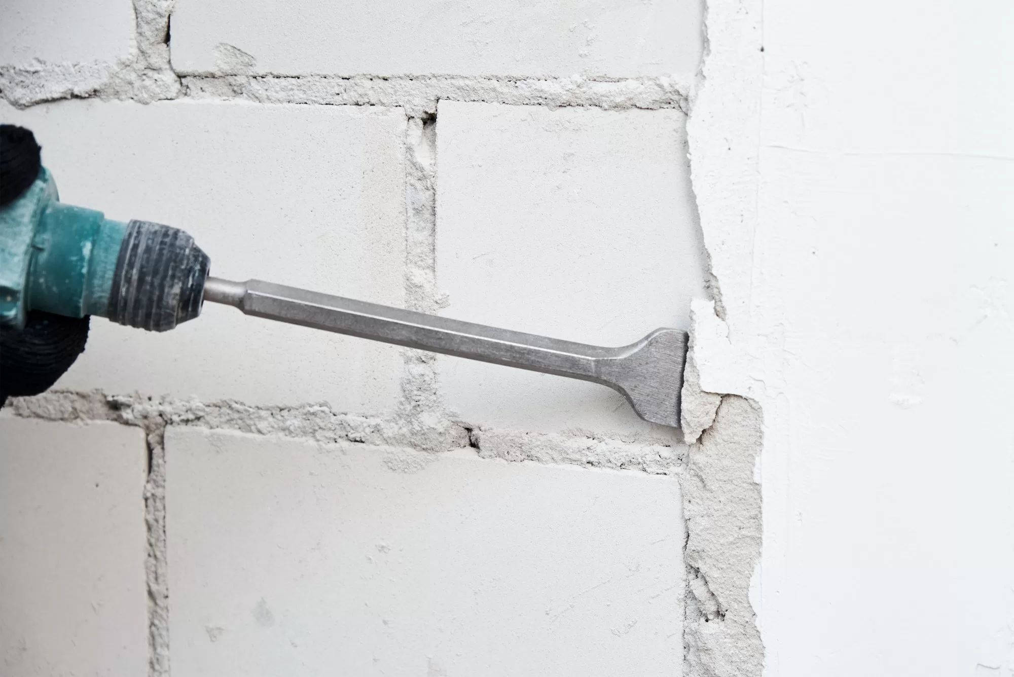 Man with demolition hammer remove stucco from wall. Renovation concept