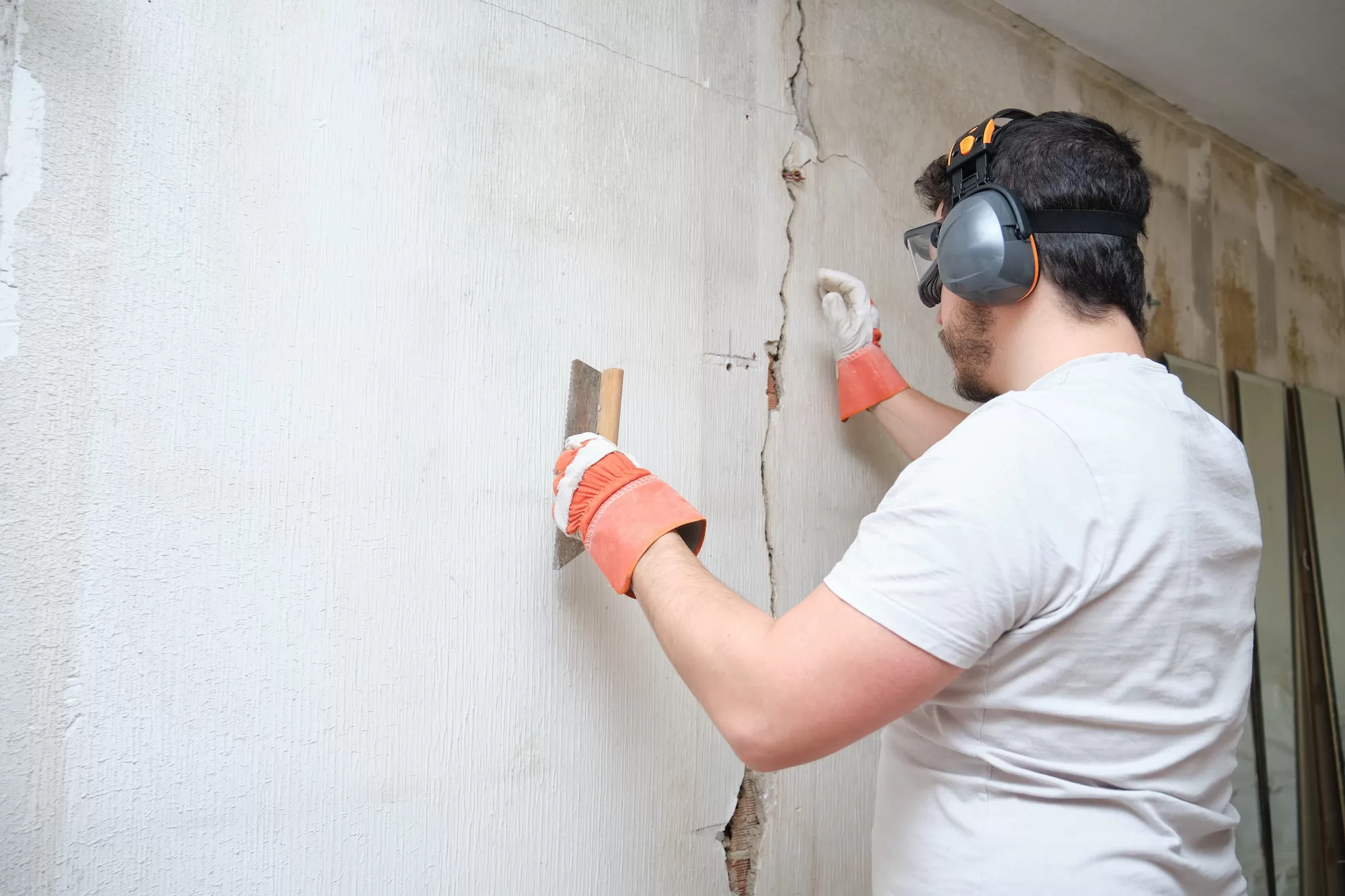 Construction worker repairing a crack, plastering cement on wall